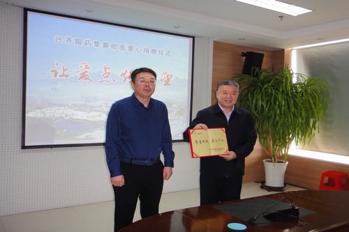 图为市残联副理事长刘佶向沈阳兴齐眼药股份有限公司董事长刘继东